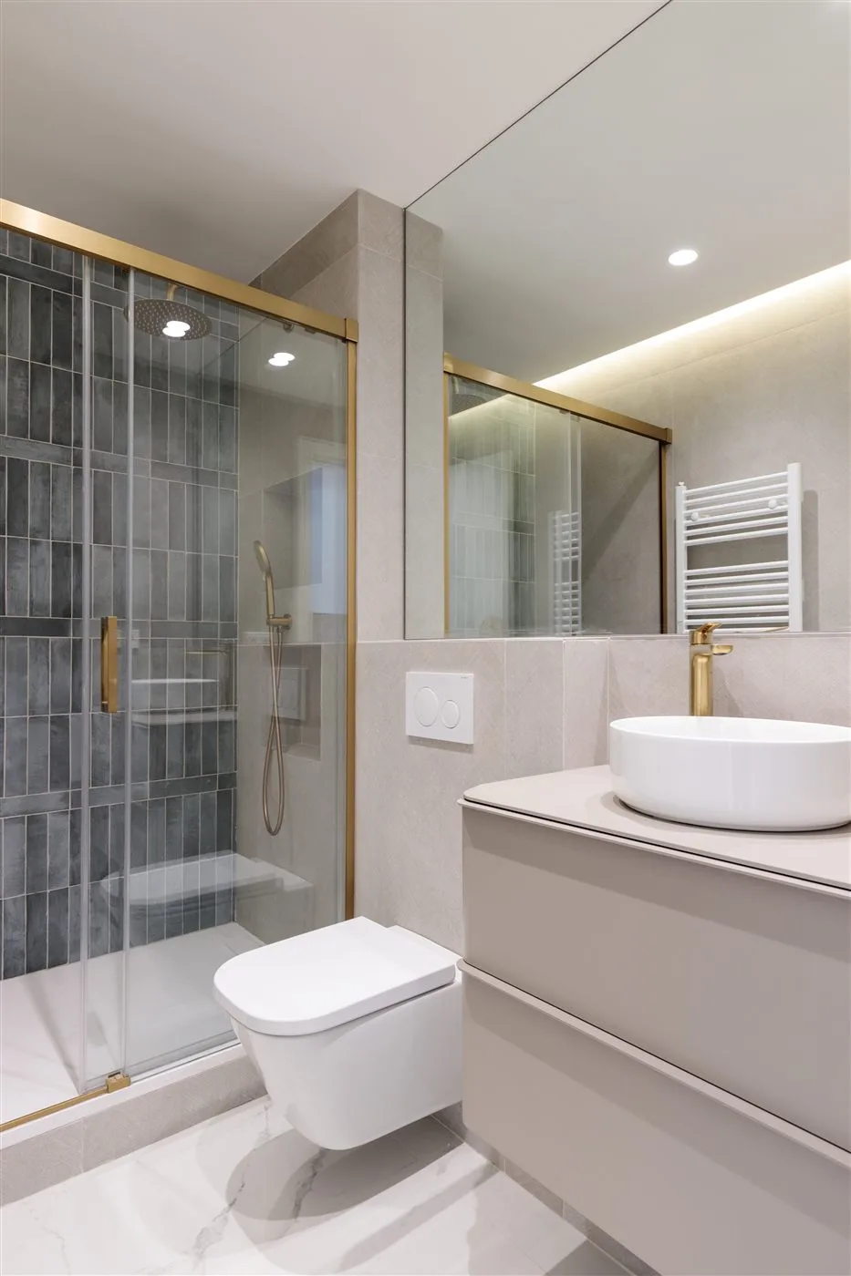 Reforma de baño beige con grifería dorada en Madrid