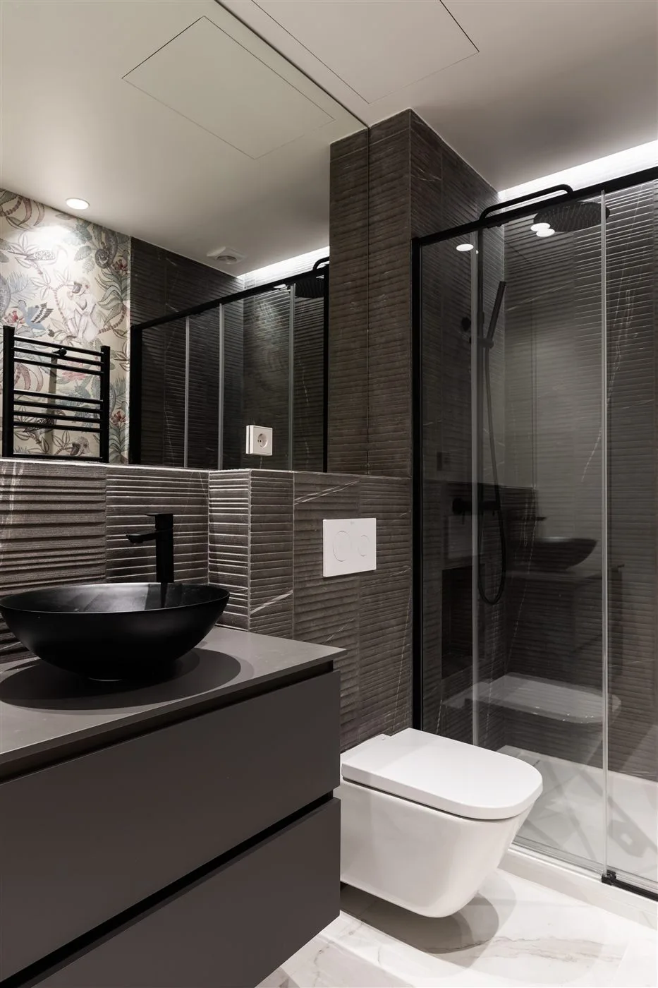 Reforma de baño gris oscuro con papel pintado floral en Madrid