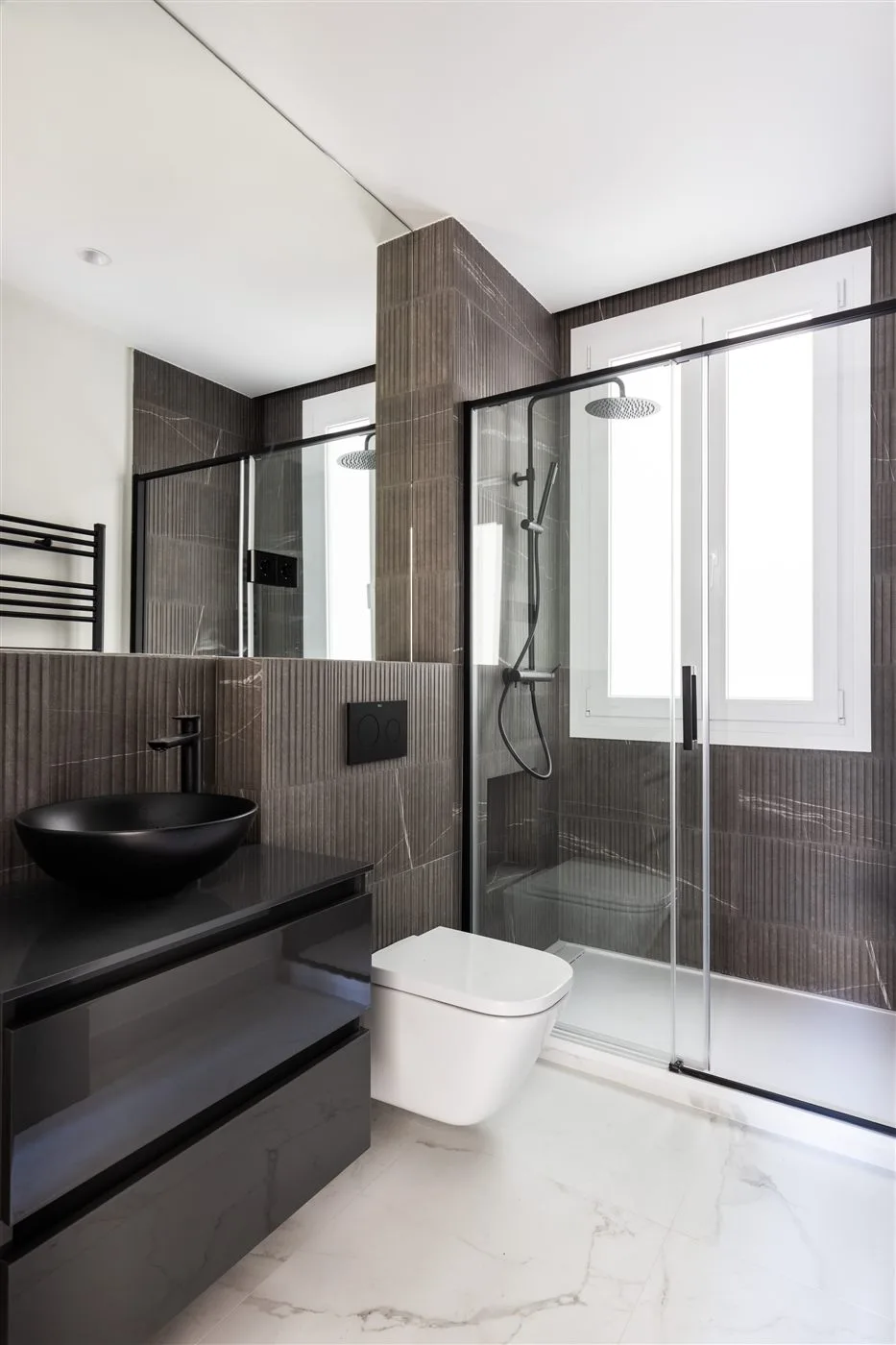 Reforma de baño premium negro con mármol, lavabo bowl y ducha en Madrid