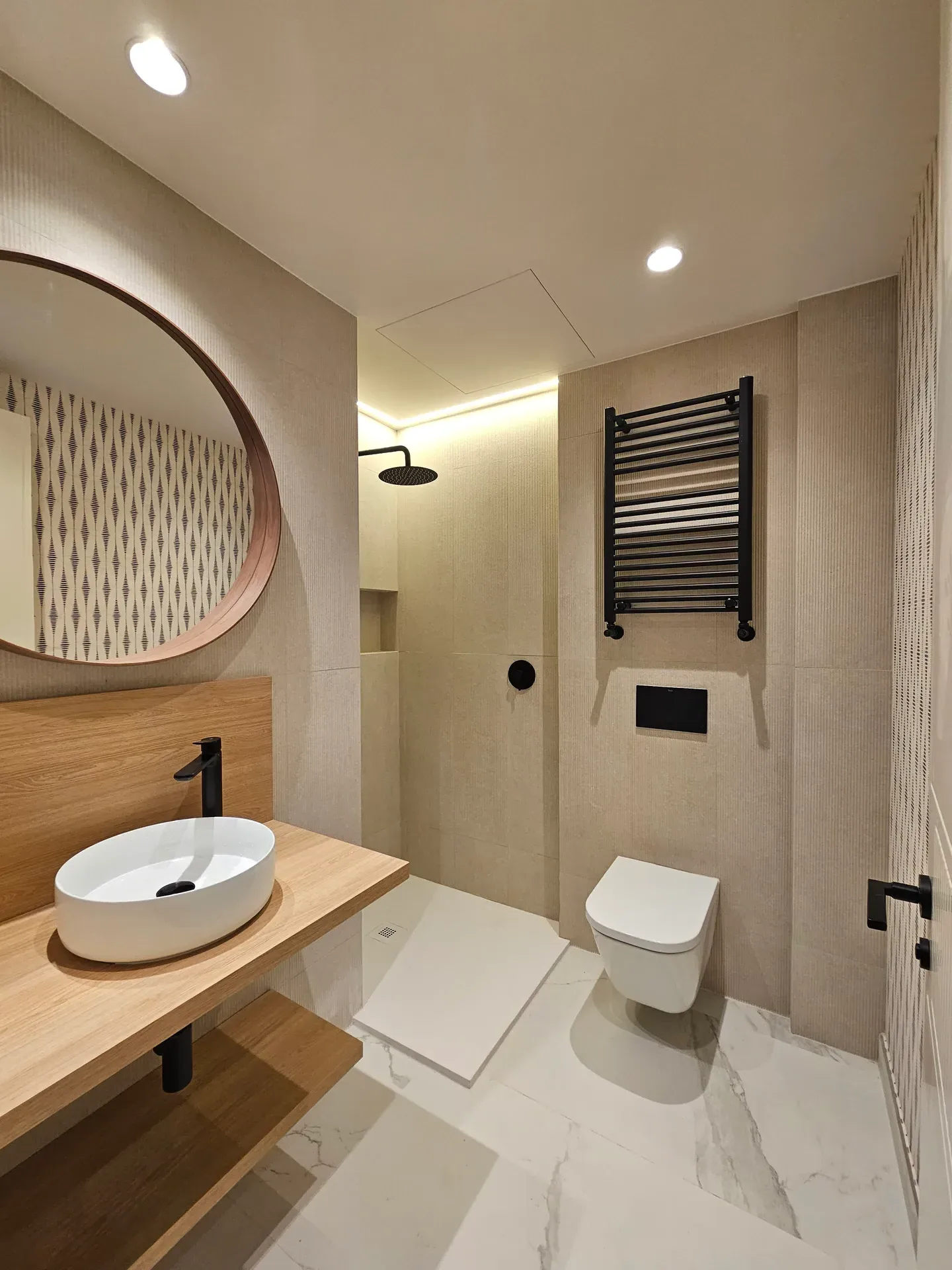 Reforma de baño beige con lavabo redondo y encimera de madera en Madrid